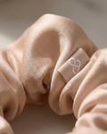 Beige scrunchie with a logo on a beige background