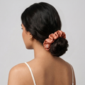 Woman with a scrunchie in her hair against a plain background