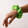 Green scrunchie on a wrist against a white background