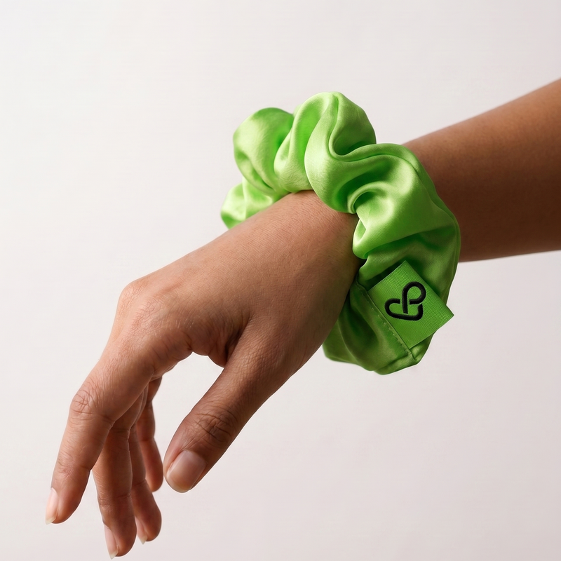 Green scrunchie on a wrist against a white background
